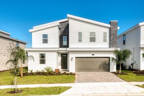 A modern two-story house with a garage, a stone chimney, and a well-maintained lawn.