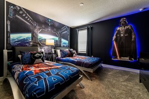 A Star Wars-themed bedroom with two beds, a large mural, and a poster of Darth Vader.