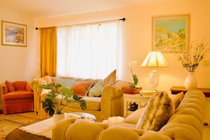 A cozy living room with a sofa, armchairs, a coffee table, and a lamp. - Charming 4bd house near the coast with backyard (Oxnard)