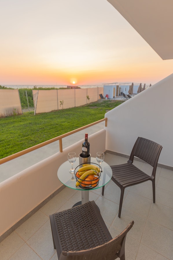 Ein Balkon mit einem Glastisch, zwei Stühlen, einer Weinflasche und einer Obstschale.