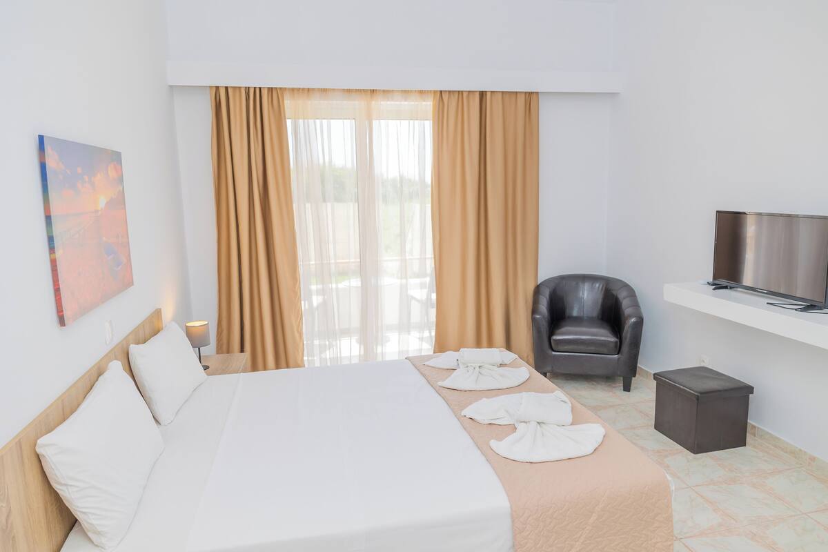 Une chambre d’hôtel avec un lit, une chaise, une télévision et un tableau au mur.