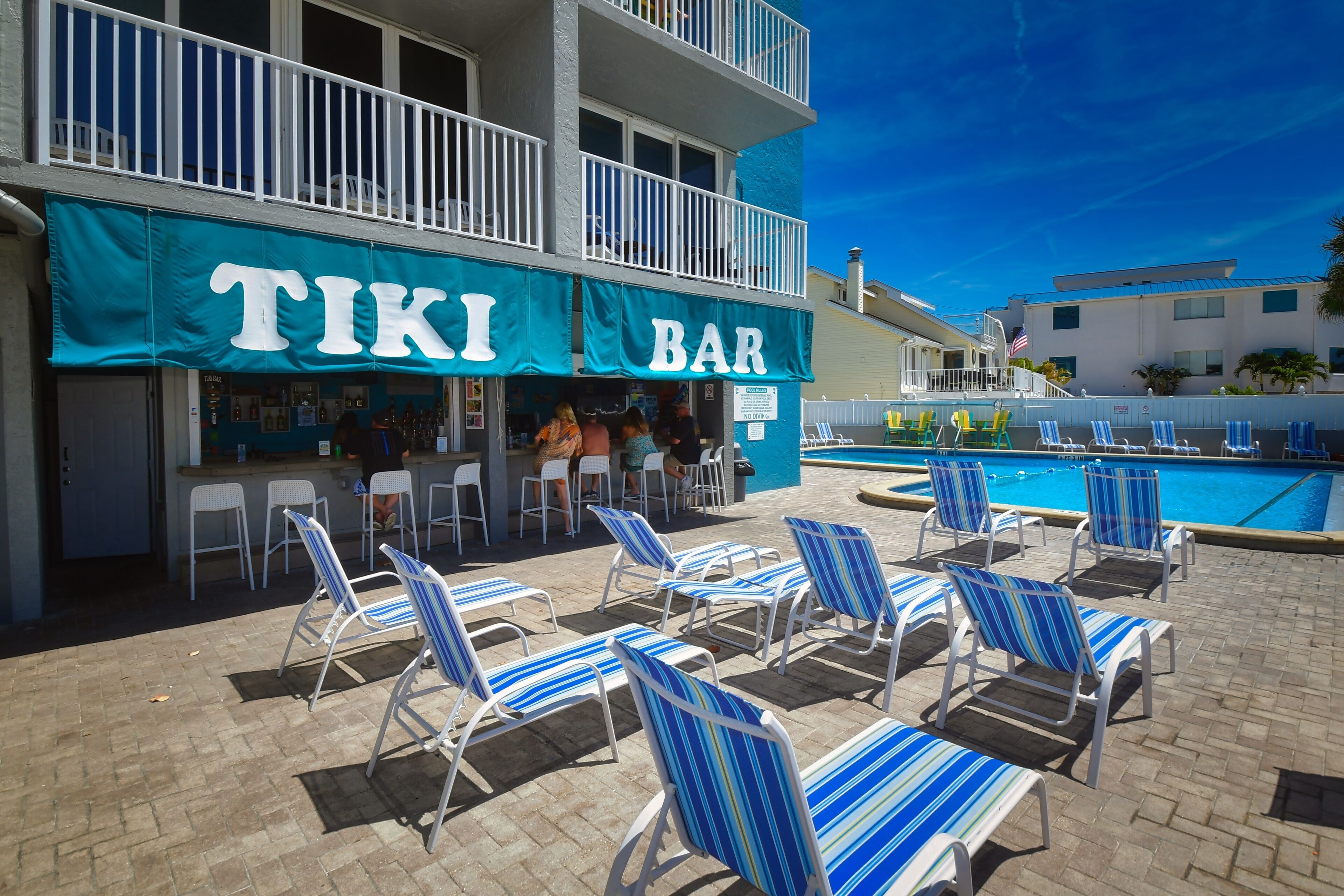 Un bar de style tiki avec des places assises à l’extérieur et un espace piscine.
