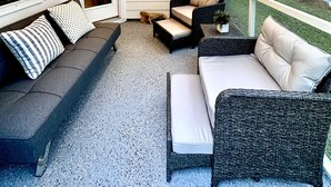 Eine überdachte Veranda mit Korbmöbeln, Lichterketten und Deckenventilator.