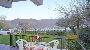 Un balcón con una mesa para dos, con vistas a un paisaje de un lago y montañas.