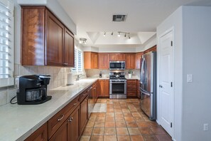A kitchen with wooden cabinets, a stainless steel refrigerator, a microwave, and a coffee maker.