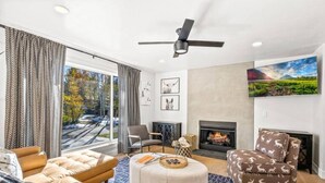 Una sala de estar moderna con chimenea, asientos cómodos y un ventanal con cortinas.