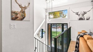 Una sala de estar moderna con una escalera, un sofá y obras de arte en las paredes.