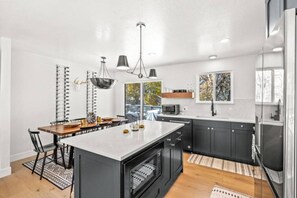 A modern kitchen with a central island, dark cabinetry, and pendant lighting. - Luxury Home in Park Meadows! (Park City)