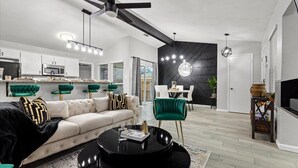 A modern living room with a sofa, a coffee table, and a dining area with chairs.