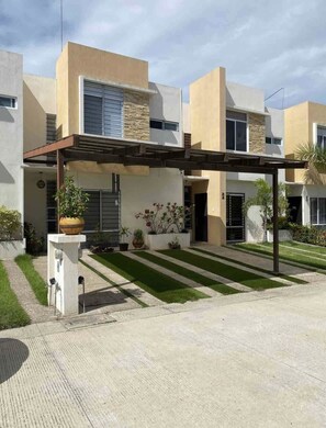Stylish building with a covered entrance, potted plants, and a small garden.