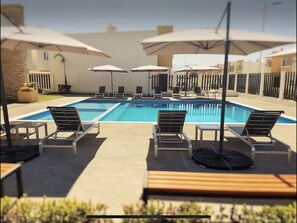 Relax by the pool surrounded by comfortable lounge chairs and lush greenery.