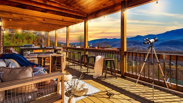 Una terraza de madera con un telescopio, asientos y una vista panorámica de la montaña.