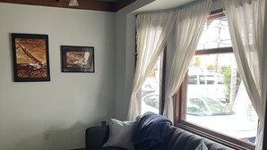 Un salon avec un canapé foncé, une petite table en bois et deux tableaux encadrés accrochés au mur.