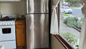 Une cuisine compacte équipée d’un réfrigérateur en acier inoxydable, d’une cuisinière à gaz et d’un four blanc.