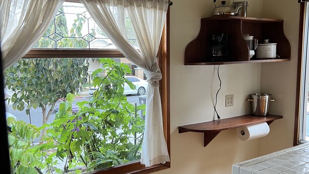 Une cuisine avec une fenêtre, un ventilateur de plafond et des étagères remplies d’ustensiles de cuisine.
