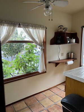 Una cocina con ventana, ventilador de techo y estantes con utensilios de cocina.