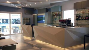 A modern bar area with a counter, seating, and a large TV screen.
