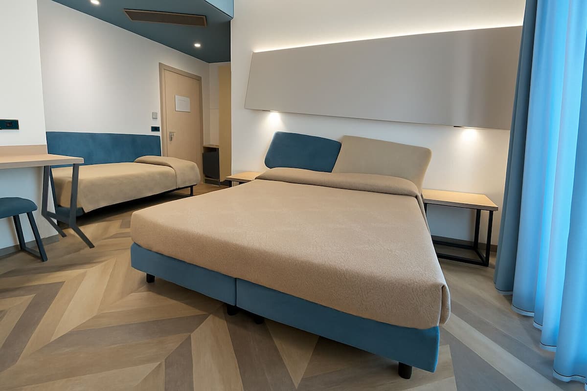 A modern hotel room with a large bed, a desk, and a chair.