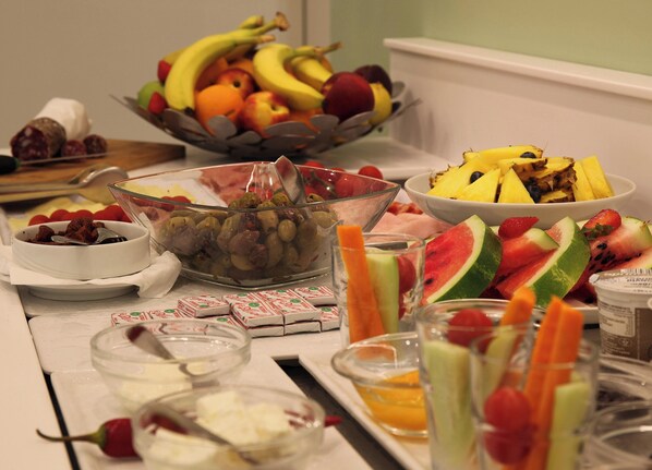 A breakfast buffet with various fruits, vegetables, and condiments.