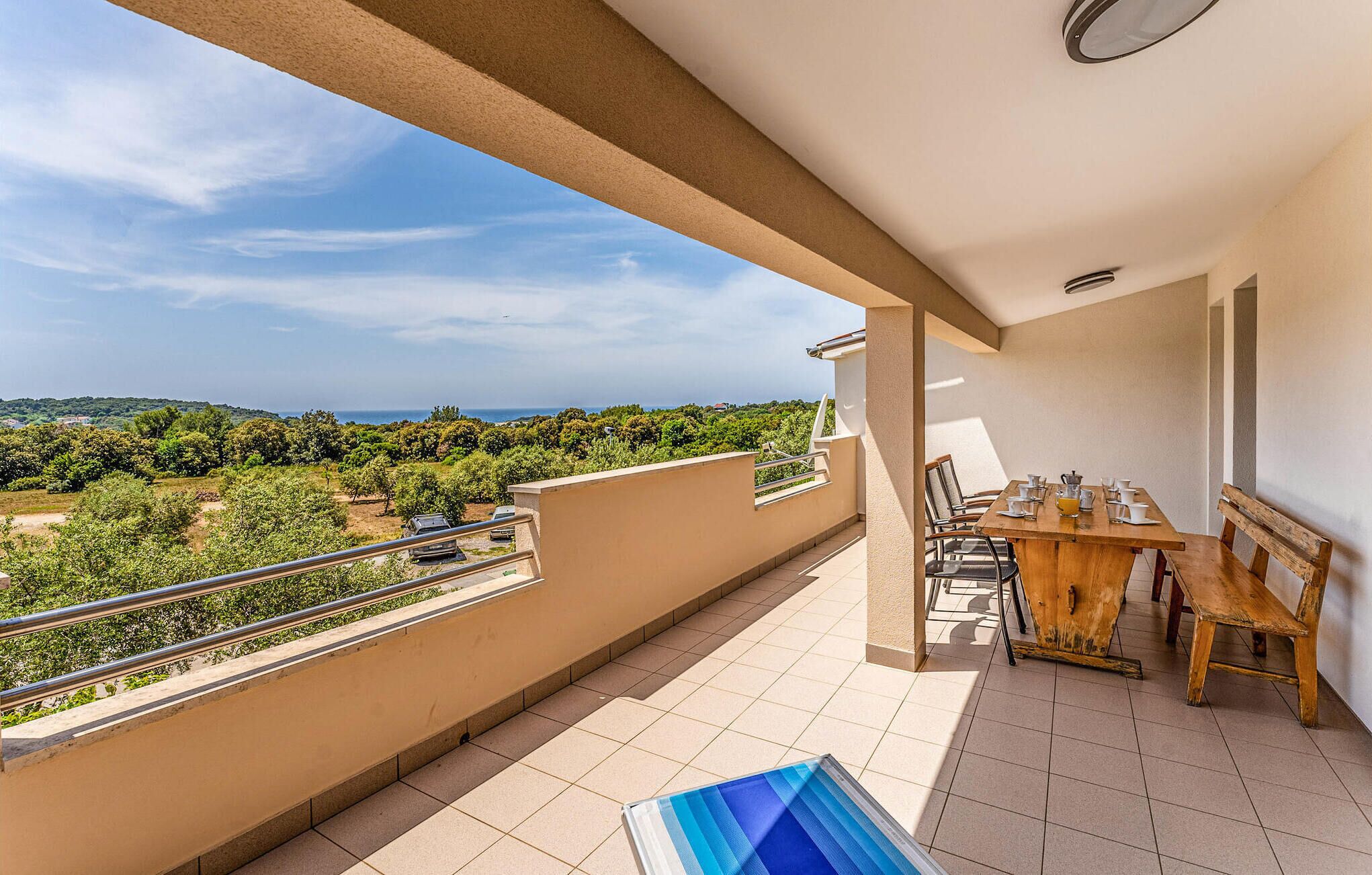 A balcony with a view of a green landscape and a distant body of water.