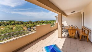 En balkon med udsigt over et grønt landskab og et fjerntliggende vandområde.