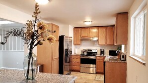 A kitchen with wooden cabinets, stainless steel appliances, a granite countertop, and a vase with dried flowers. - Spacious & Quiet Home Near DeKoevend Park (Centennial)