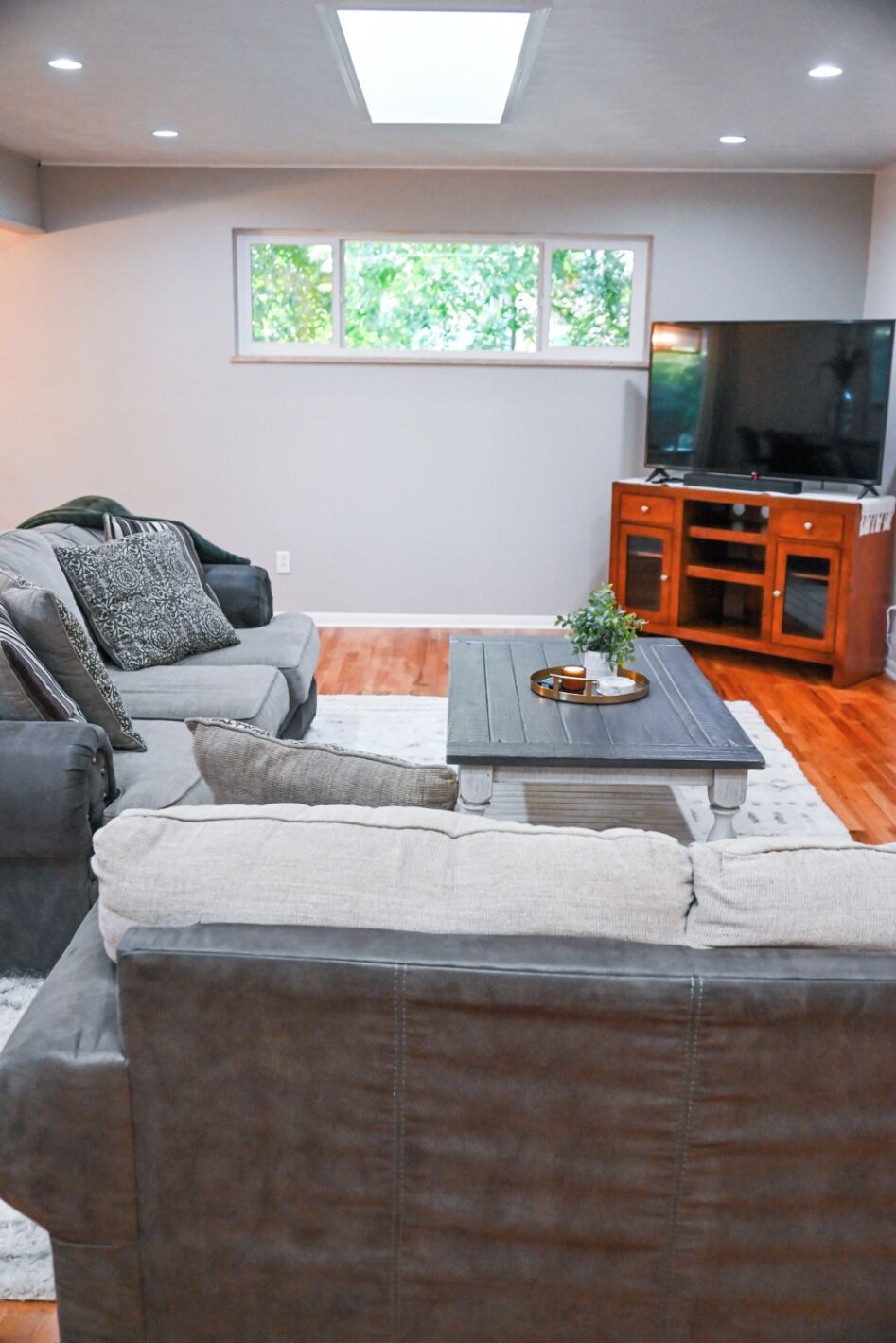 Una sala moderna con un sofá gris, una mesa de centro y un televisor.