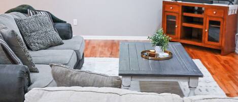Una sala moderna con un sofá gris, una mesa de centro y un televisor.