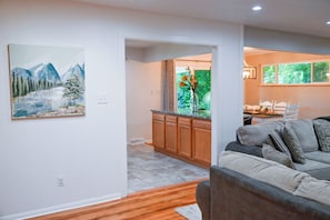 A modern living room with a grey sofa, wooden flooring, and a painting of a mountain landscape. - Spacious, Quiet Home in Centennial (Centennial)