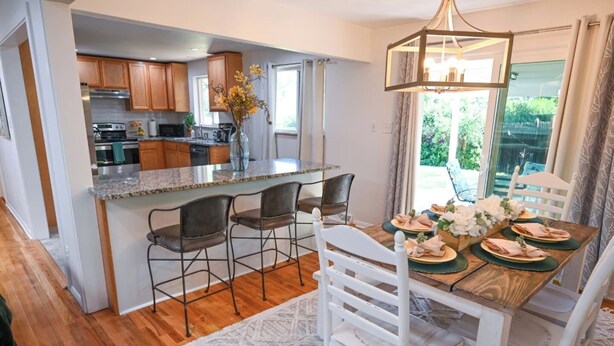 A kitchen with wooden cabinets, a granite countertop, and a dining area with a wooden table and chairs. - Spacious & Quiet Home Near DeKoevend Park (Centennial)
