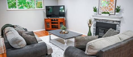 A living room with a fireplace, a television, and a sofa set.