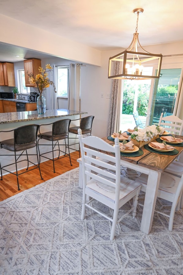 A dining area with a wooden table, white chairs, and a chandelier.
