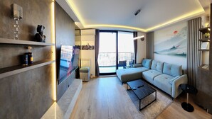 Un salon moderne avec un canapé, une table basse et un téléviseur posé sur une étagère.