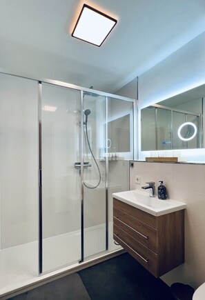 Enjoy a refreshing shower in the sleek bathroom with a glass-enclosed shower, vanity, and mirror.