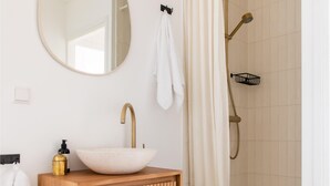 A bathroom with a round mirror, a vessel sink, a gold faucet, a towel rack, and a shower with a gold showerhead. - 2 bedroom nice home in Den Oever (Den Oever)