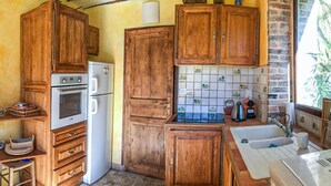 Una cocina rústica con armarios de madera, un refrigerador, un horno y un salpicadero de azulejos con baldosas decorativas.