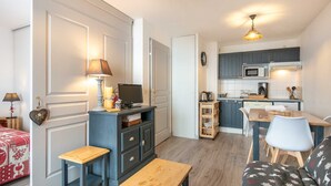 A compact living space with a kitchenette, a dining area, and a seating area with a television and decorative items. - Modern studio 4 ppl, balcony, near the ski runs (Saint-Sorlin-d´Arves)