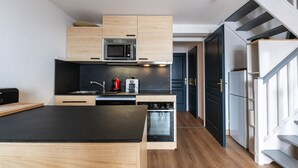 Une cuisine compacte dotée de meubles en bois, d’un four à micro-ondes, d’une machine à café et d’un lave-vaisselle.