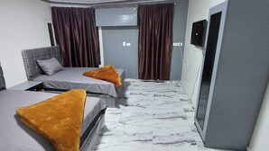 A hotel room with two beds, a marble floor, and a grey door. - Best Dreams Hotel (Giza)