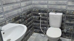 A bathroom with a sink, toilet, and shower. The walls are tiled with a marble-like pattern. - Best Dreams Hotel (Giza)