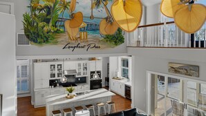 Una cocina moderna con armarios blancos, una isla central y vistas al exterior.