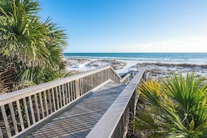 A wooden boardwalk leading to a beach with a clear view of the ocean.