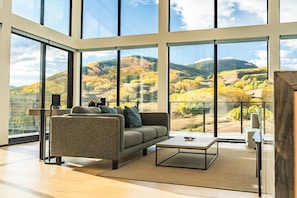 A spacious living room with a large window offering a view of a mountainous landscape.