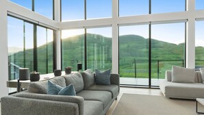 A modern living room with a large window offering a view of green hills.