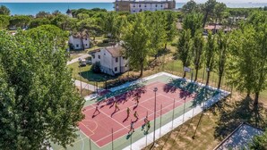 An aerial view of a residential area with a basketball court, a white house, and a building with a red roof. - Beach front apartment (Cavallino-Treporti)