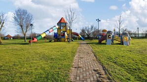 A playground with a slide, climbing structures, and a brick pathway. - Beach front apartment (Cavallino-Treporti)