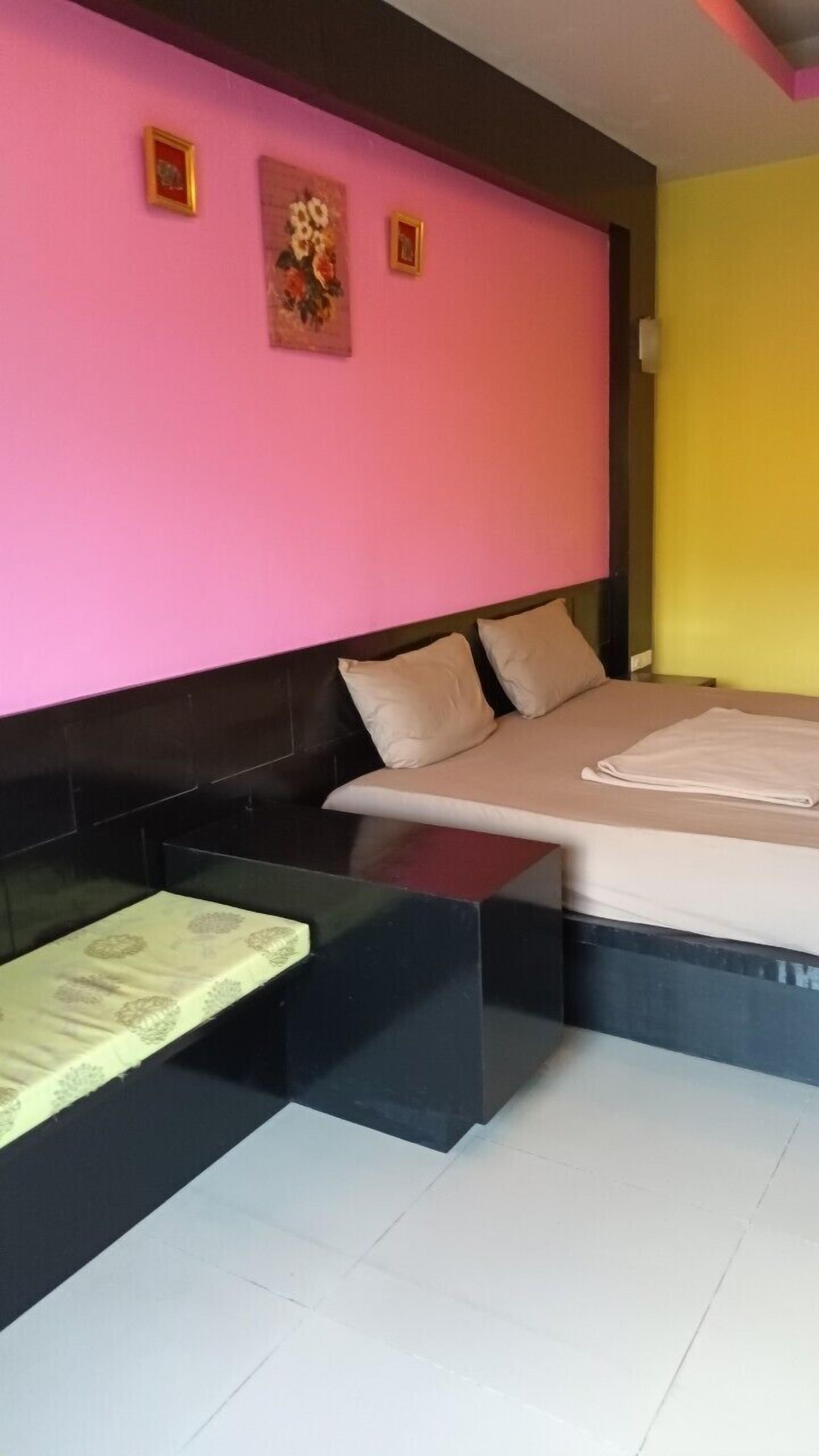 A modern bedroom with a pink and yellow color scheme, a bed with beige bedding, and a black headboard.