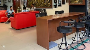 A modern lobby with a red sofa, a wooden reception desk, and a bar area with stools. - Lavender Patong Hotel (Patong)