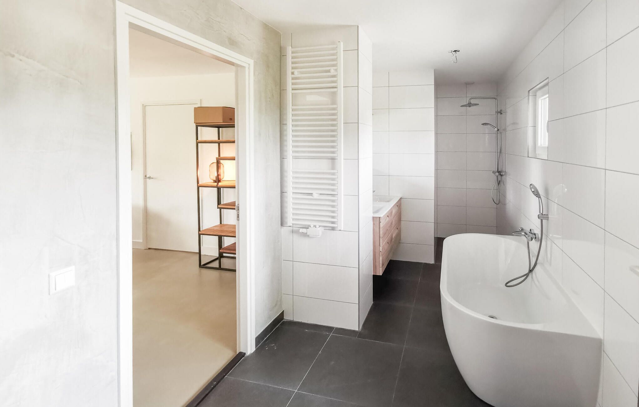 A modern bathroom with a freestanding bathtub, a shower area, and a built-in shelf unit with a mirror.