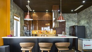 A modern bar area with a marble countertop, three bar stools, and a refrigerator branded "SANAKY". - BBQ Villa & Hostel Ha Long (Bai Chay)